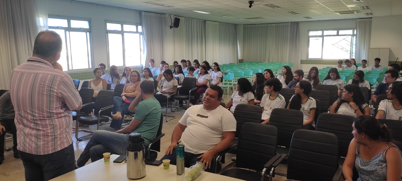 Foto dos participantes  no Auditório ouvindo as orientações do coordenador do Comitê de Ética em Pesquisas (CEP) do IFES (que aparece de costas, no lado esquerdo da imagem).