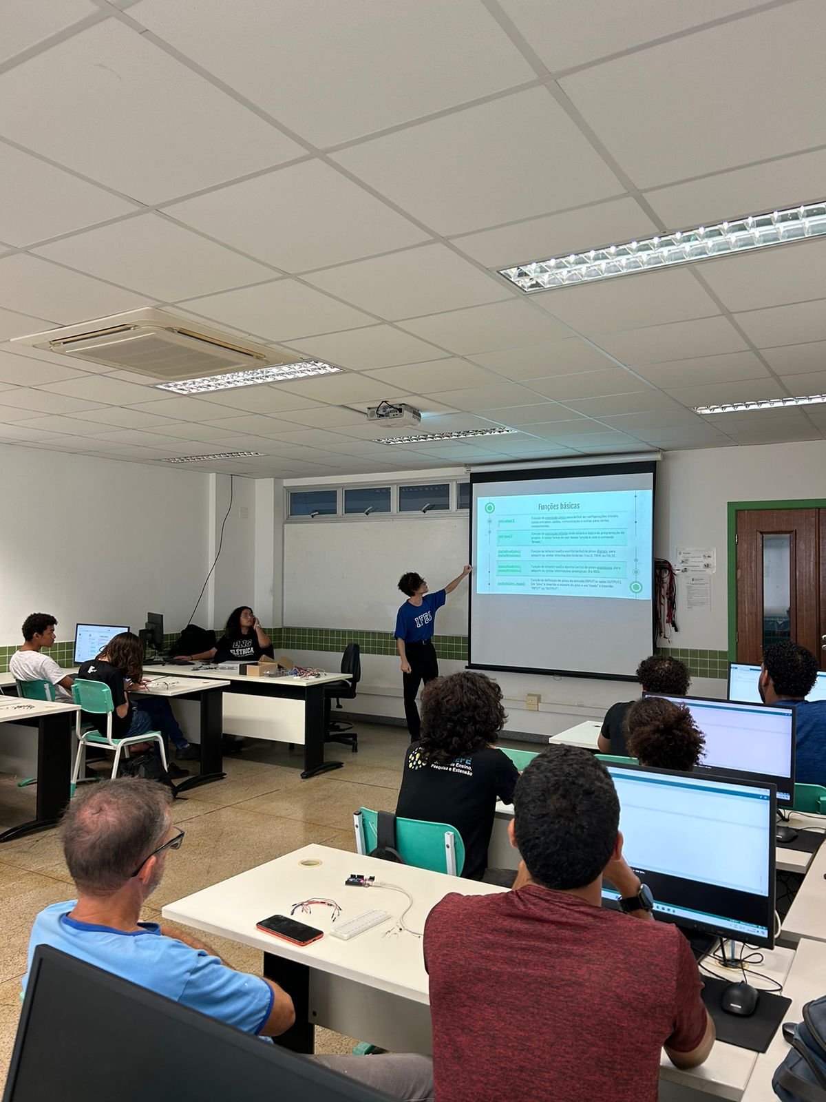 Em uma sala de aula, estudantes est&atilde;o sentados em dupla e participam de minicurso ministrado por alunos e alunas de Engenharia El&eacute;trica.