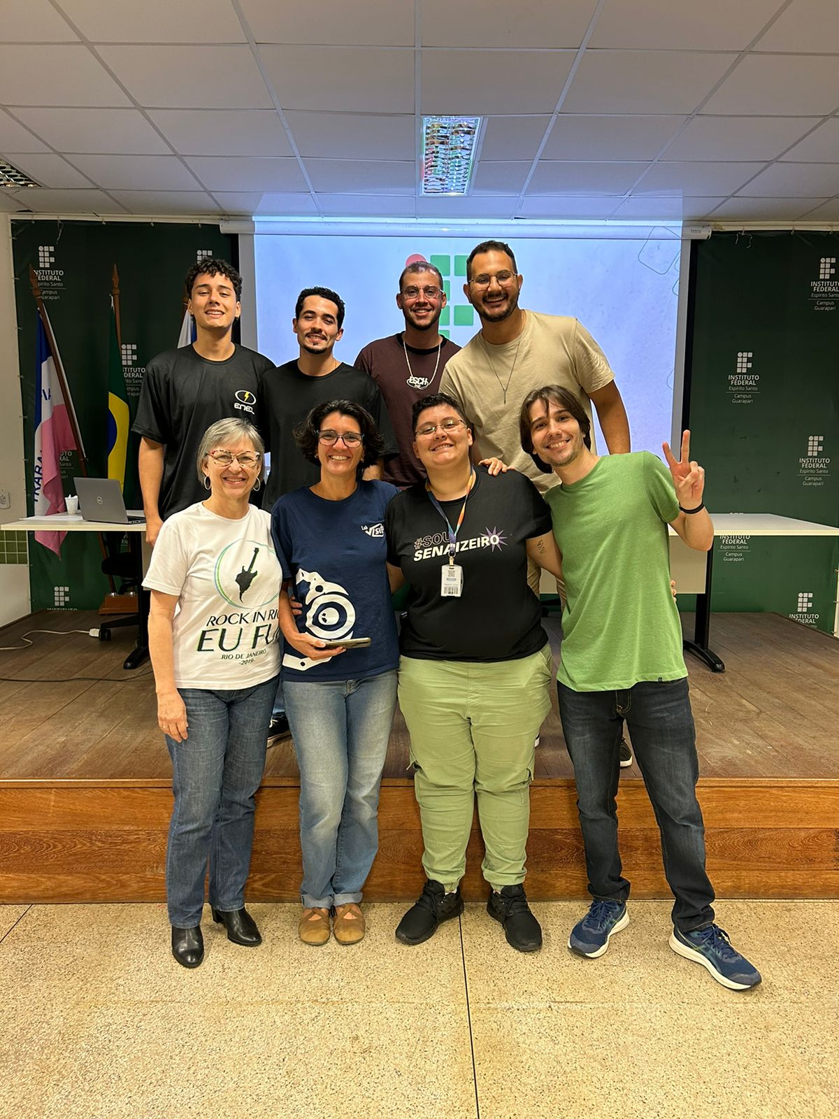 No palco do Audit&oacute;rio, oito pessoas posam para a foto. Entre eles, palestrantes, professores e membros do Centro Acad&ecirc;mico.