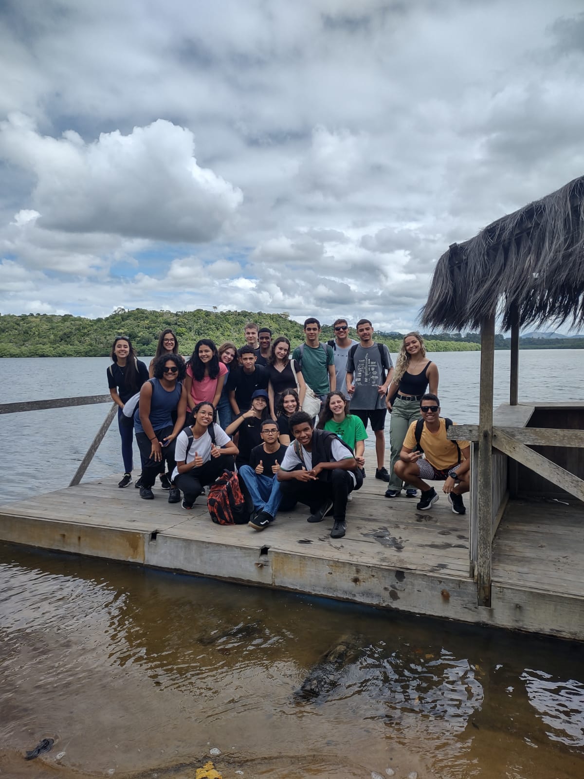 Estudantes posam para foto &agrave; beira de um pier, pr&oacute;ximo &agrave;s  aguas de um rio.
